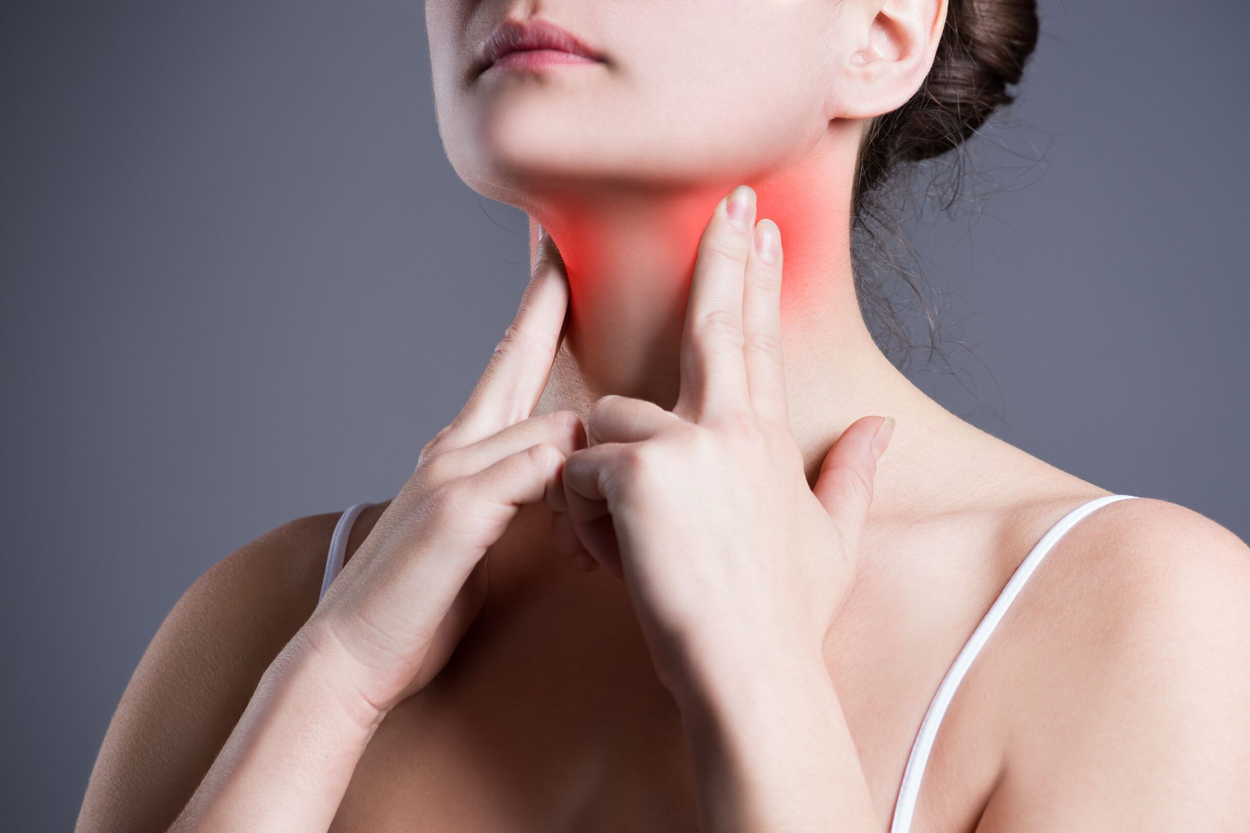 Mujer tocándose la zona tiroidea del cuello, destacada en rojo para representar síntomas relacionados con el hipertiroidismo.