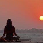 Persona meditando al atardecer frente al horizonte, simbolizando la conciencia, la intención y la conexión mente-realidad según Jacobo Grinberg y la Ley de Atracción.