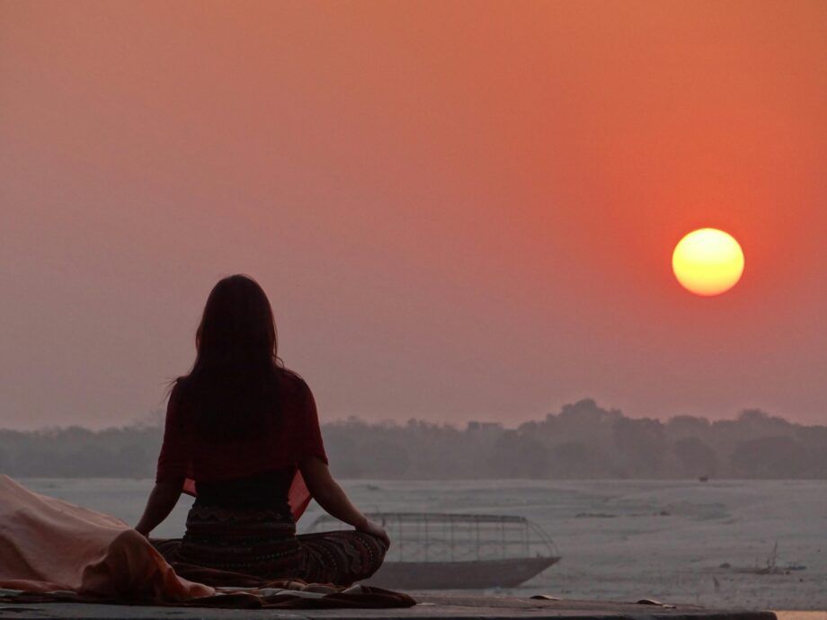 Persona meditando al atardecer frente al horizonte, simbolizando la conciencia, la intención y la conexión mente-realidad según Jacobo Grinberg y la Ley de Atracción.