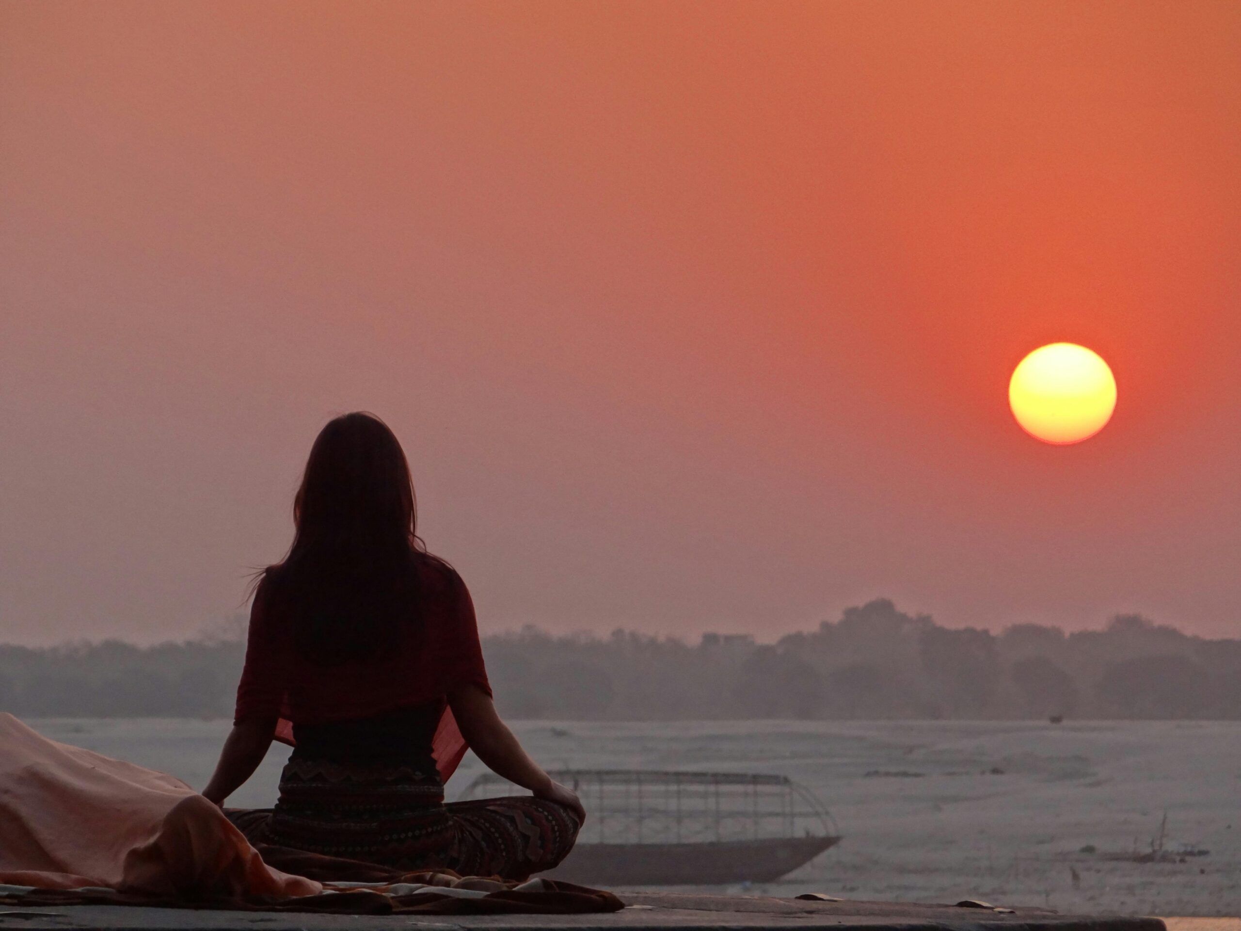 Persona meditando al atardecer frente al horizonte, simbolizando la conciencia, la intención y la conexión mente-realidad según Jacobo Grinberg y la Ley de Atracción.