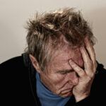 Hombre con gesto de agotamiento y estrés, llevándose la mano al rostro, símbolo del impacto del cortisol elevado.