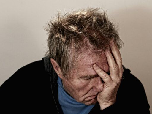 Hombre con gesto de agotamiento y estrés, llevándose la mano al rostro, símbolo del impacto del cortisol elevado.