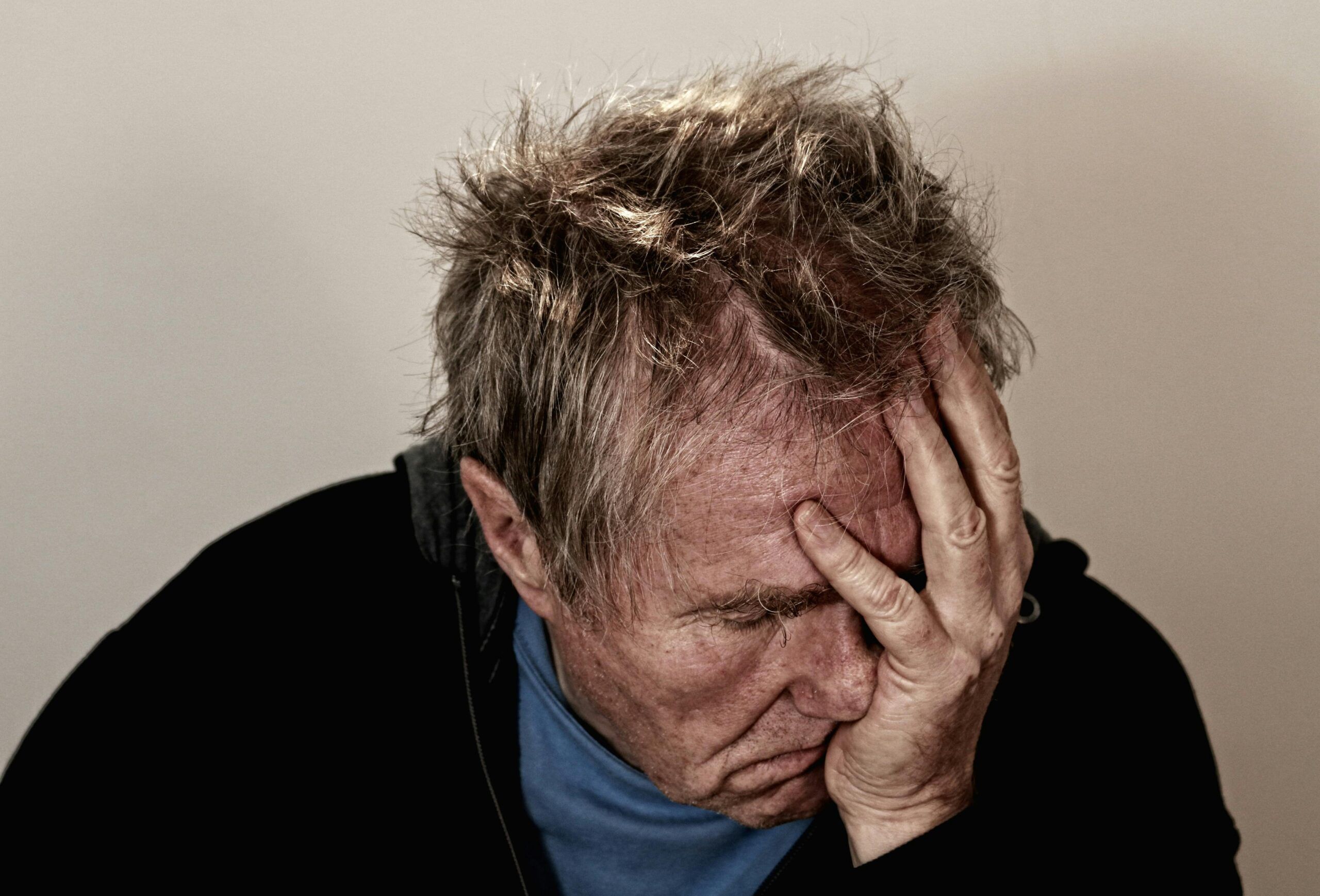Hombre con gesto de agotamiento y estrés, llevándose la mano al rostro, símbolo del impacto del cortisol elevado.