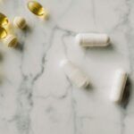 Varias cápsulas y perlas de suplementos sobre una superficie de mármol, simbolizando diferentes tipos de magnesio utilizados en suplementación.