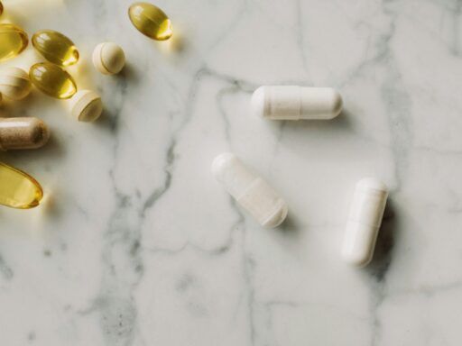 Varias cápsulas y perlas de suplementos sobre una superficie de mármol, simbolizando diferentes tipos de magnesio utilizados en suplementación.