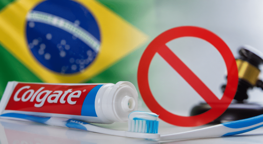 Pasta dental Colgate con cepillo de dientes y bandera de Brasil al fondo, simbolizando la polémica sobre su posible prohibición.
