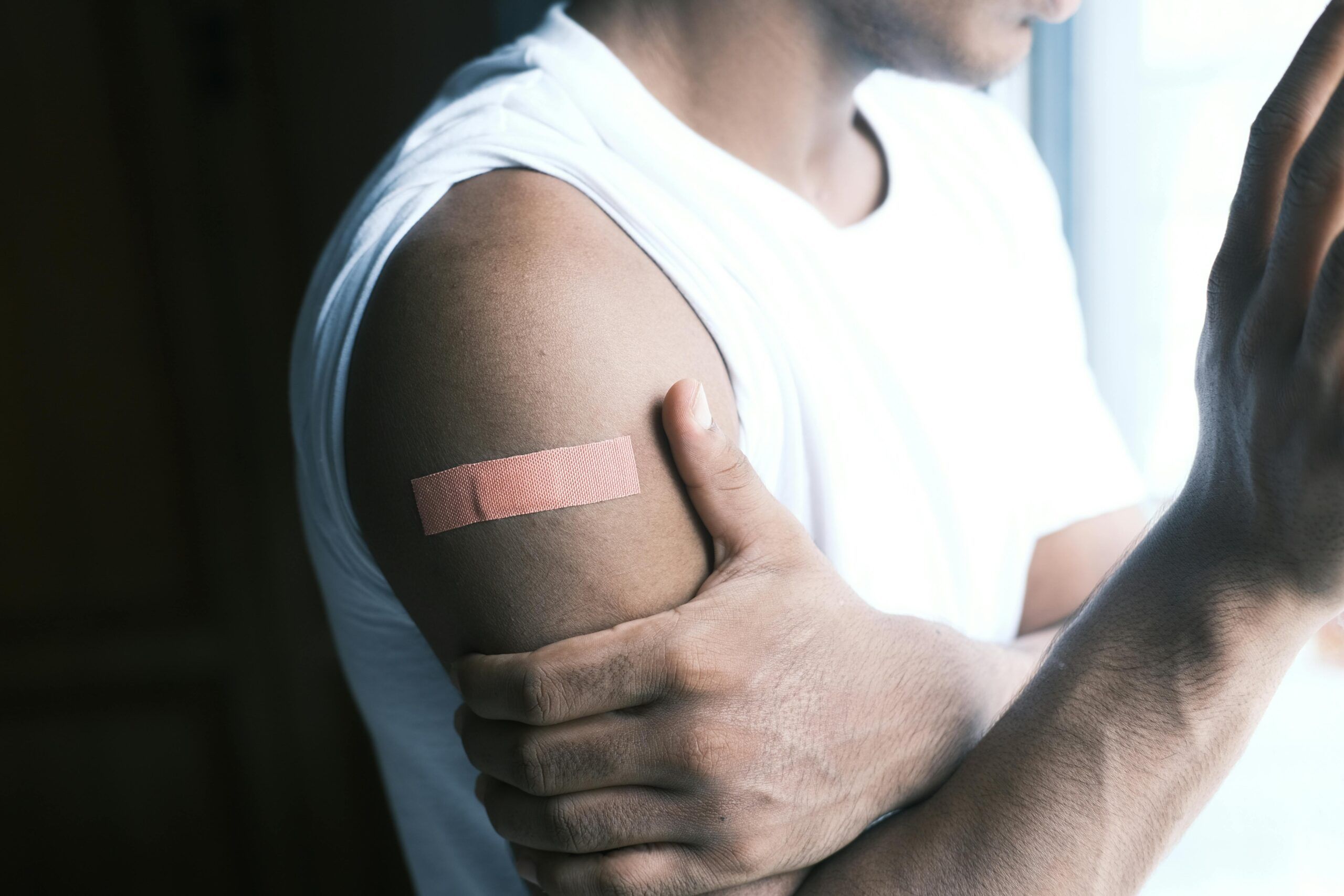 Hombre con una tirita adhesiva en el brazo ilustrando el uso de productos sanitarios y la posible exposición a químicos.