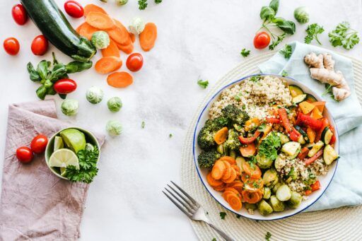 Plato saludable con quinoa y verduras frescas: brócoli, zanahorias, calabacín, pimientos y coles de Bruselas, representando bienestar y nutrición consciente.