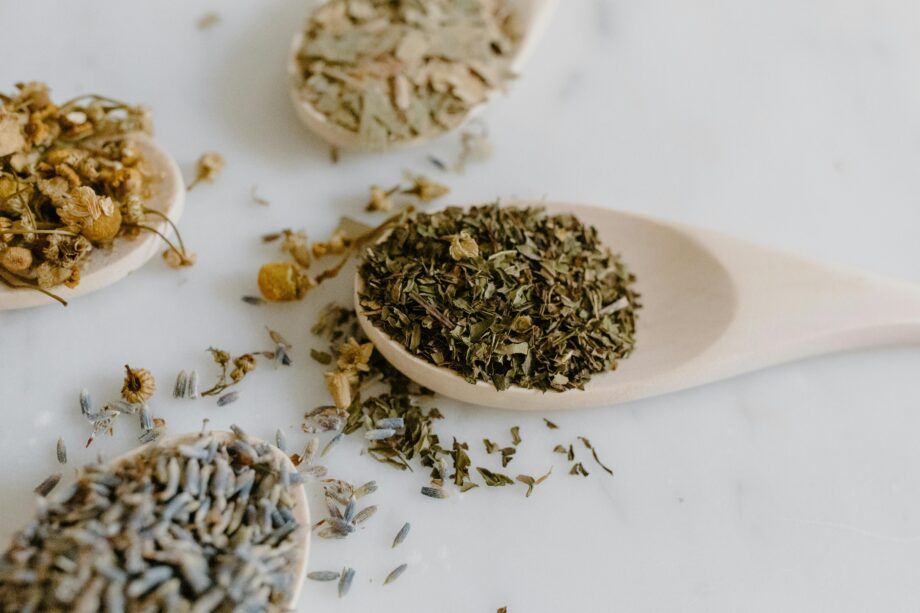 Primer plano de cucharas de madera con manzanilla, lavanda y otras hierbas secas usadas para infusiones relajantes contra la ansiedad.