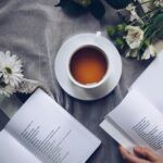 Taza de té natural para dormir profundamente junto a libros y flores, ideal para mejorar el sueño.