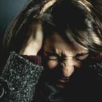 Mujer con gesto de angustia y las manos en la cabeza, mostrando tensión y sobrecarga emocional típica del estrés crónico.