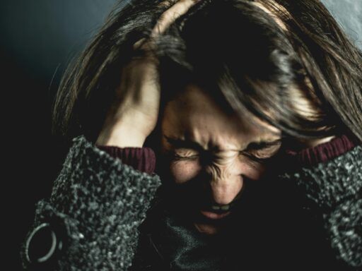 Mujer con gesto de angustia y las manos en la cabeza, mostrando tensión y sobrecarga emocional típica del estrés crónico.
