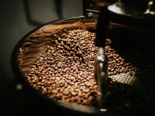 Granos de café tostados moviéndose dentro de una tostadora industrial.