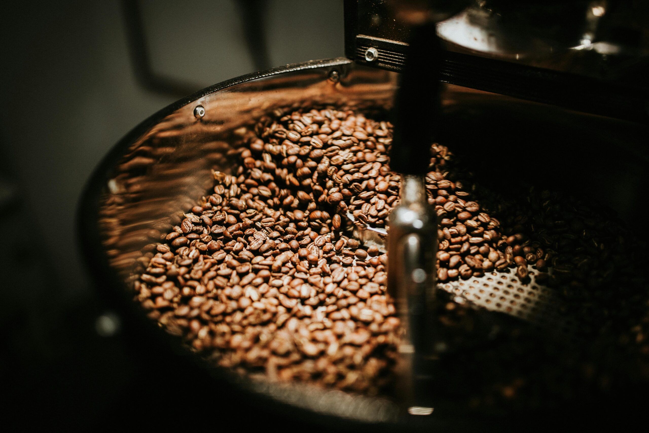 Granos de café tostados moviéndose dentro de una tostadora industrial.
