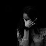 Persona cubriéndose el rostro con la mano en un gesto de tristeza, representando el peso de las heridas emocionales que pueden abordarse con constelaciones familiares.