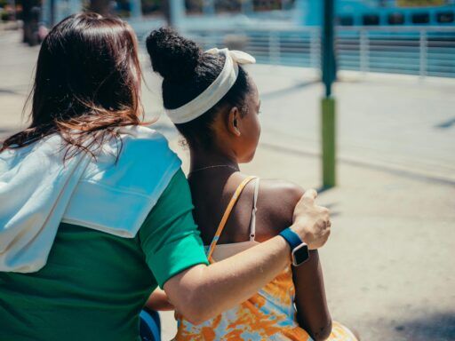 Mujer acompañando con el brazo a una niña en un gesto de apoyo, simbolizando el vínculo, la contención y el proceso emocional en la adopción desde la mirada de las constelaciones familiares.