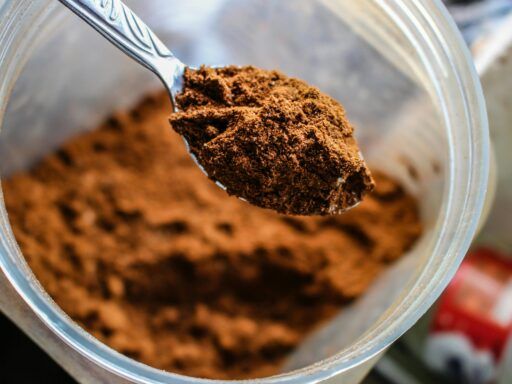 Cucharada de proteína en polvo dentro de un envase, utilizada como suplemento alimenticio, asociada a posibles riesgos por contaminación con plomo.
