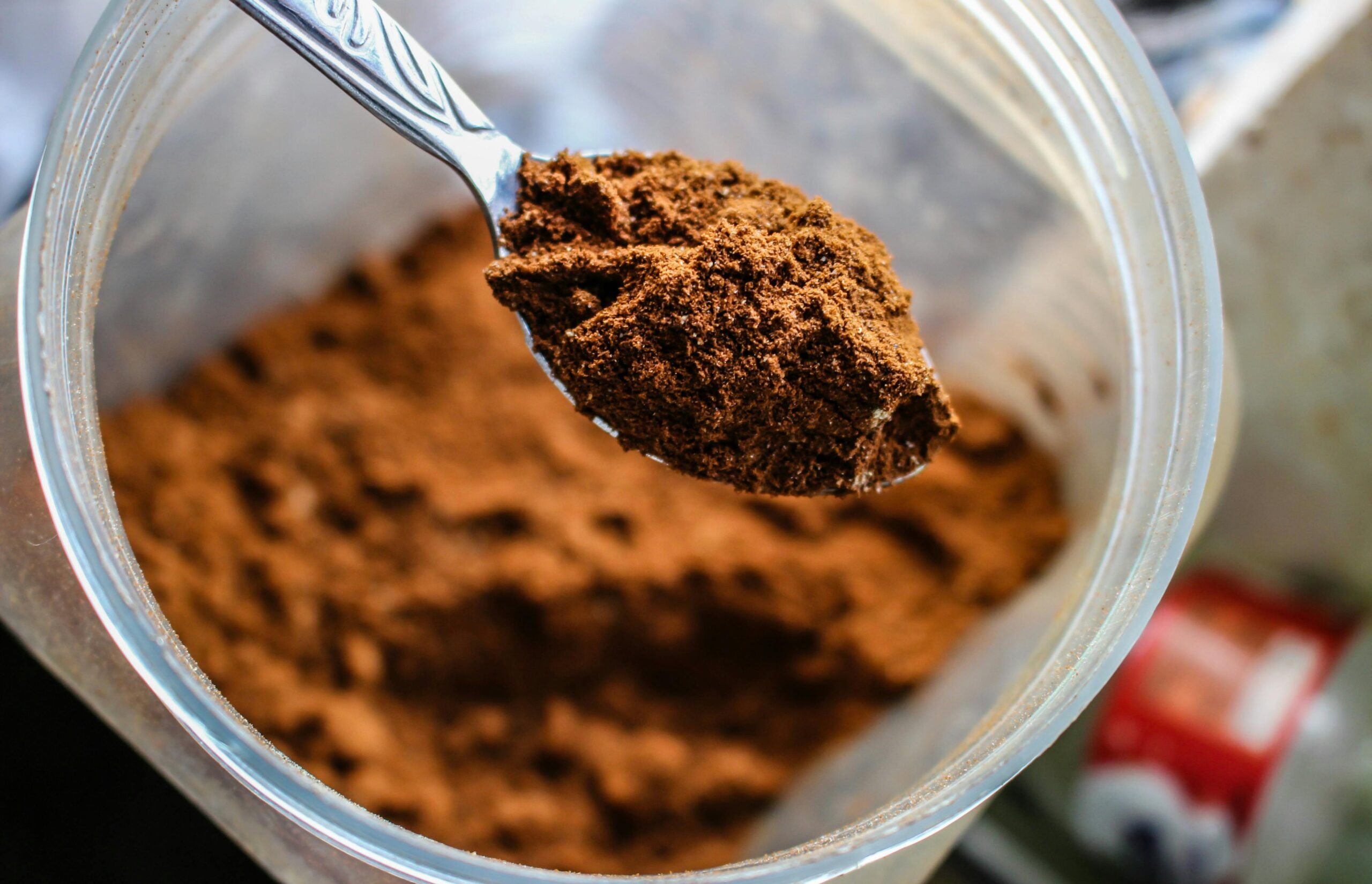 Cucharada de proteína en polvo dentro de un envase, utilizada como suplemento alimenticio, asociada a posibles riesgos por contaminación con plomo.