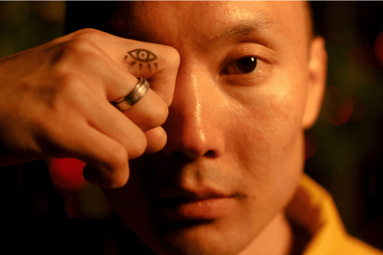 Persona con un símbolo de un ojo en la mano frente al rostro, representando el concepto del tercer ojo y la percepción interna.