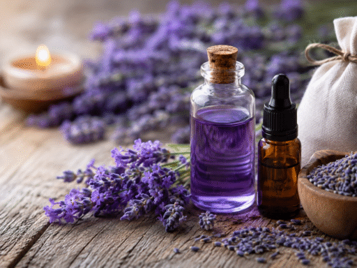 Flores de lavanda frescas junto a un frasco de aceite esencial sobre una mesa de madera, representando los beneficios de la lavanda para la salud, el descanso y la relajación.