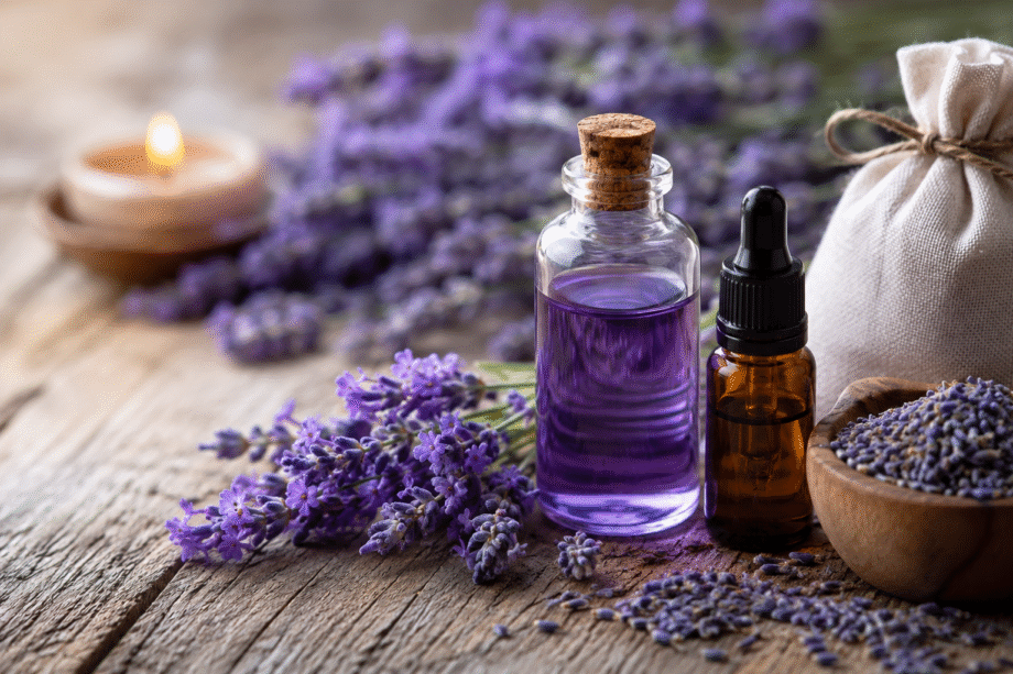 Flores de lavanda frescas junto a un frasco de aceite esencial sobre una mesa de madera, representando los beneficios de la lavanda para la salud, el descanso y la relajación.