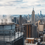 Torre de refrigeración industrial en primer plano con el horizonte de Nueva York al fondo.
