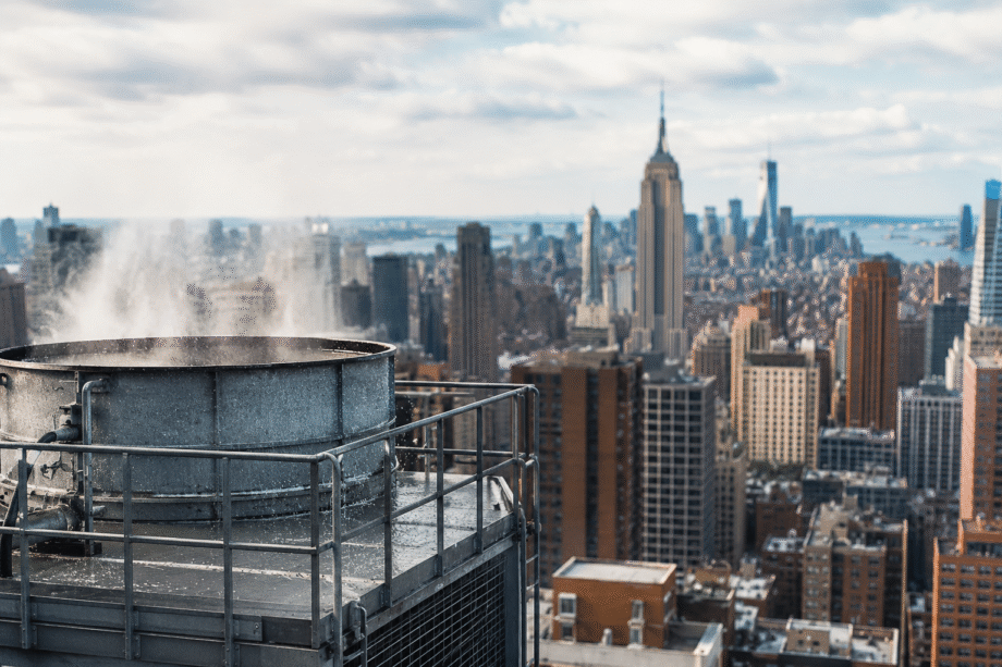 Torre de refrigeración industrial en primer plano con el horizonte de Nueva York al fondo.