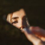 Ojo de una mujer reflejado en un fragmento de espejo, relacionado con el narcisismo y las constelaciones familiares.