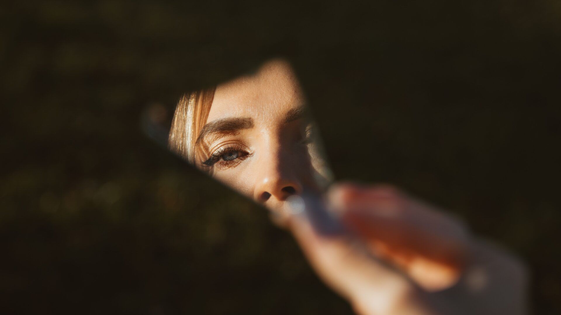 Ojo de una mujer reflejado en un fragmento de espejo, relacionado con el narcisismo y las constelaciones familiares.