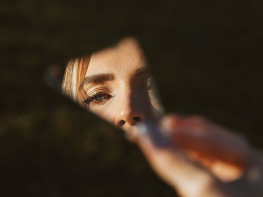 Ojo de una mujer reflejado en un fragmento de espejo, relacionado con el narcisismo y las constelaciones familiares.