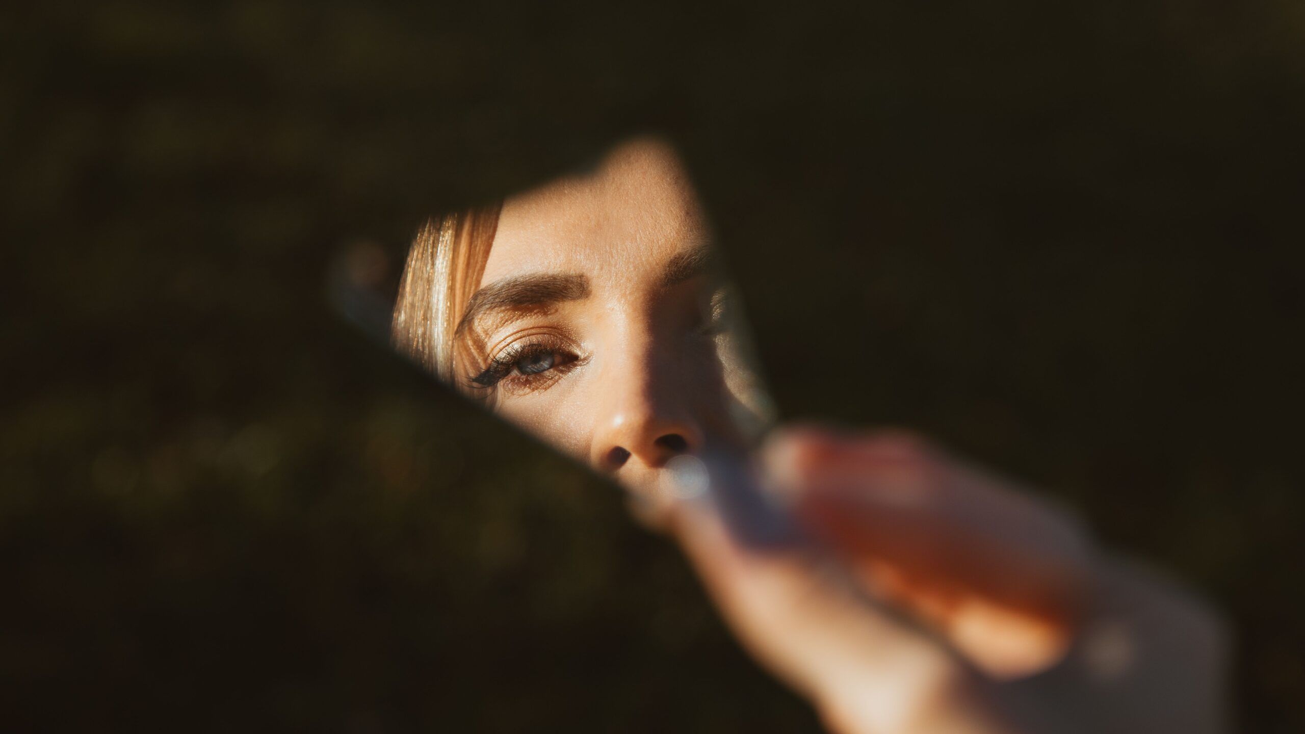 Ojo de una mujer reflejado en un fragmento de espejo, relacionado con el narcisismo y las constelaciones familiares.